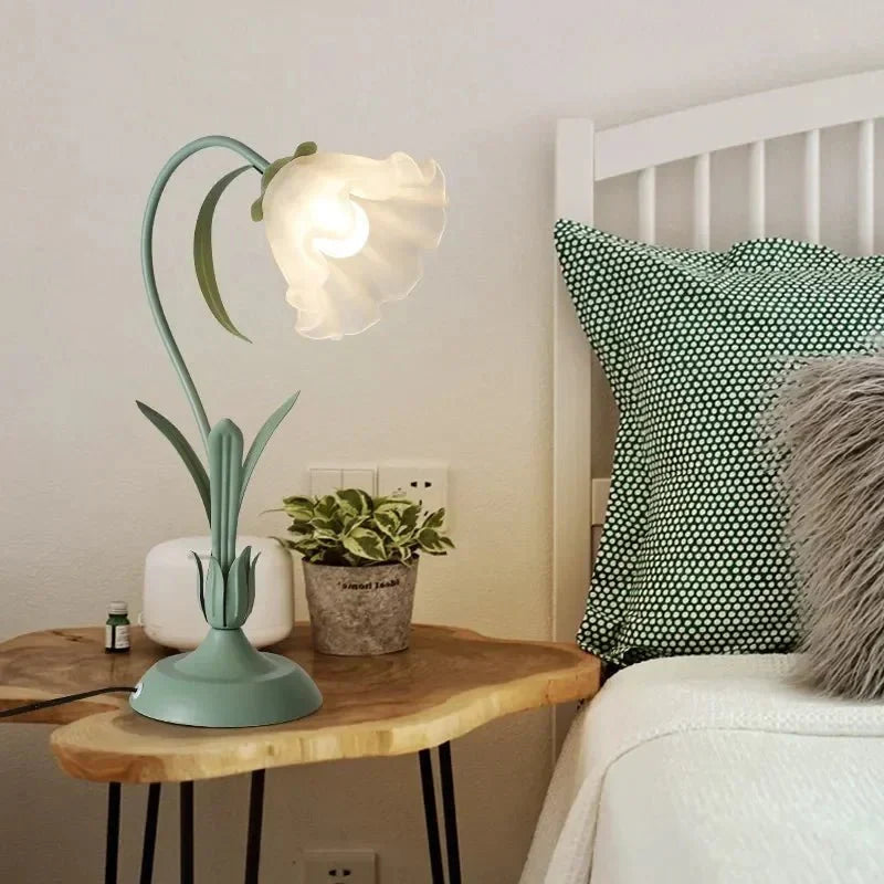Bordlampe i blomsterform placeret på natbord