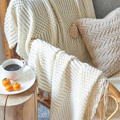 Strikket tæppe med skandinavisk design i cremefarve på sofa