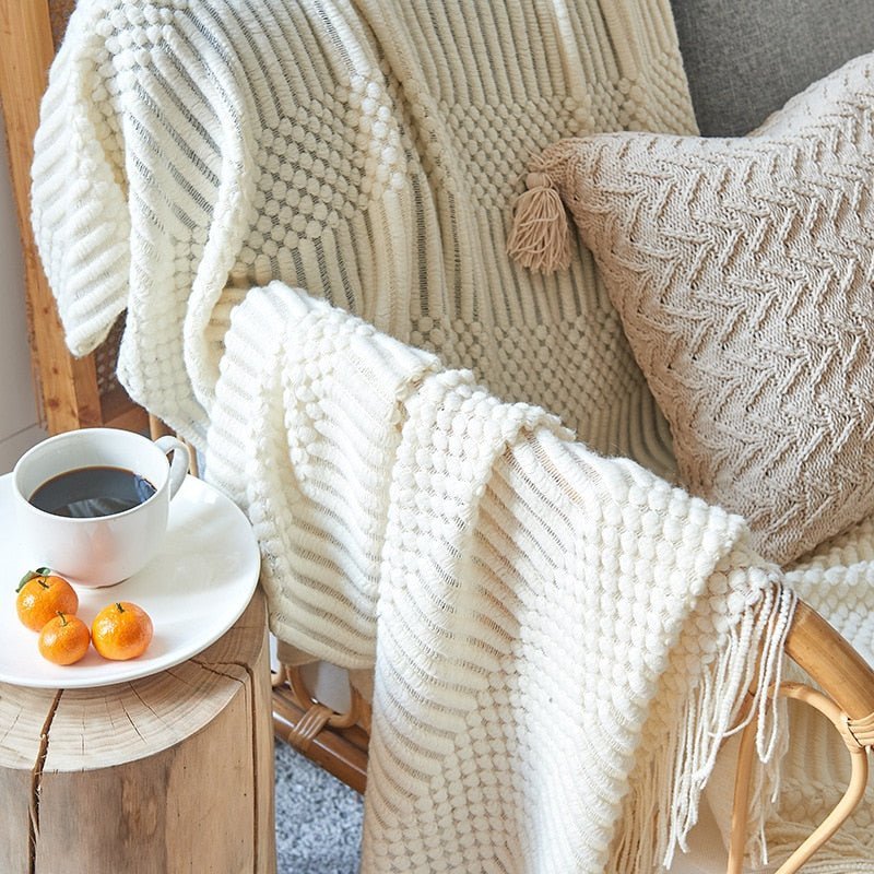 Strikket tæppe i beige farve på seng